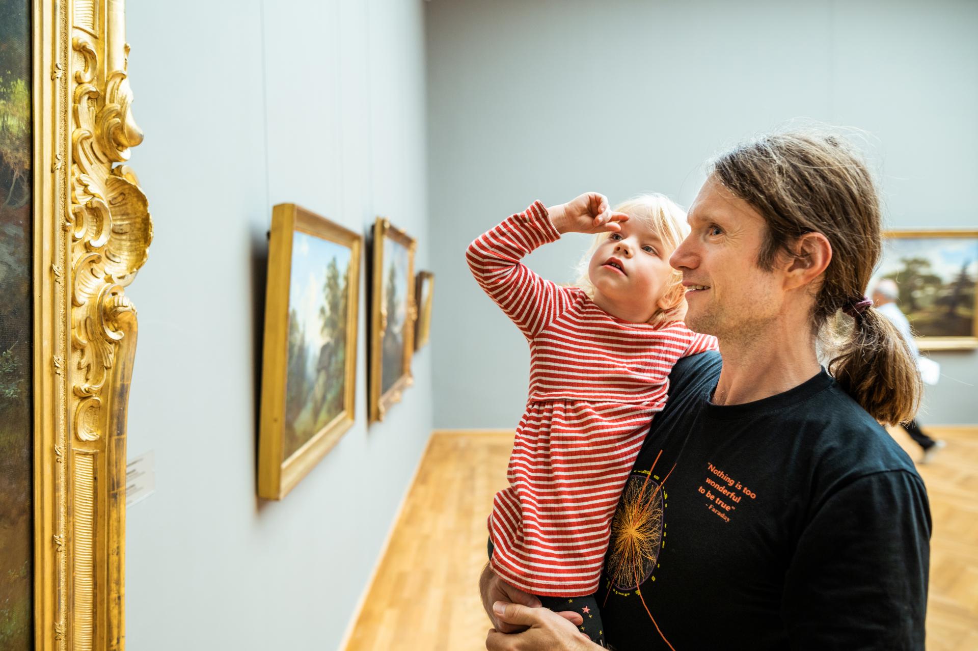 Ein Vater betrachtet gemeinsam mit seinem Kind ein Kunstwerk.