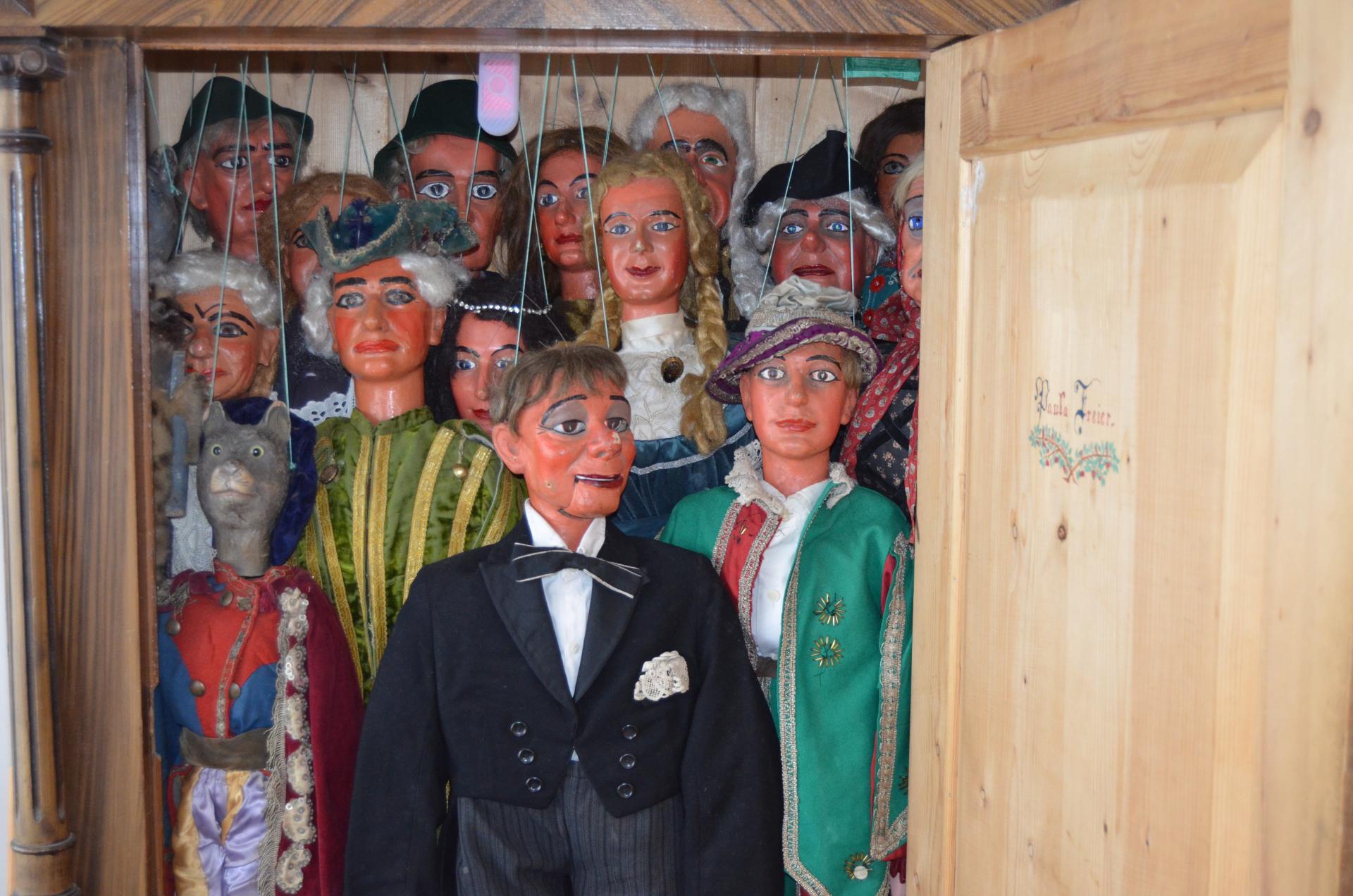 Marionettenpuppen aufgehängt in offenem Schrank, den Betrachtenden anschauend.